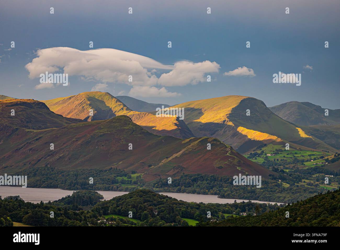La lumière dorée du matin illumine les pentes montagneuses accidentées au-dessus de Derwentwater avec des nuages dramatiques dans le Lake District National Park, Cumbria. Banque D'Images