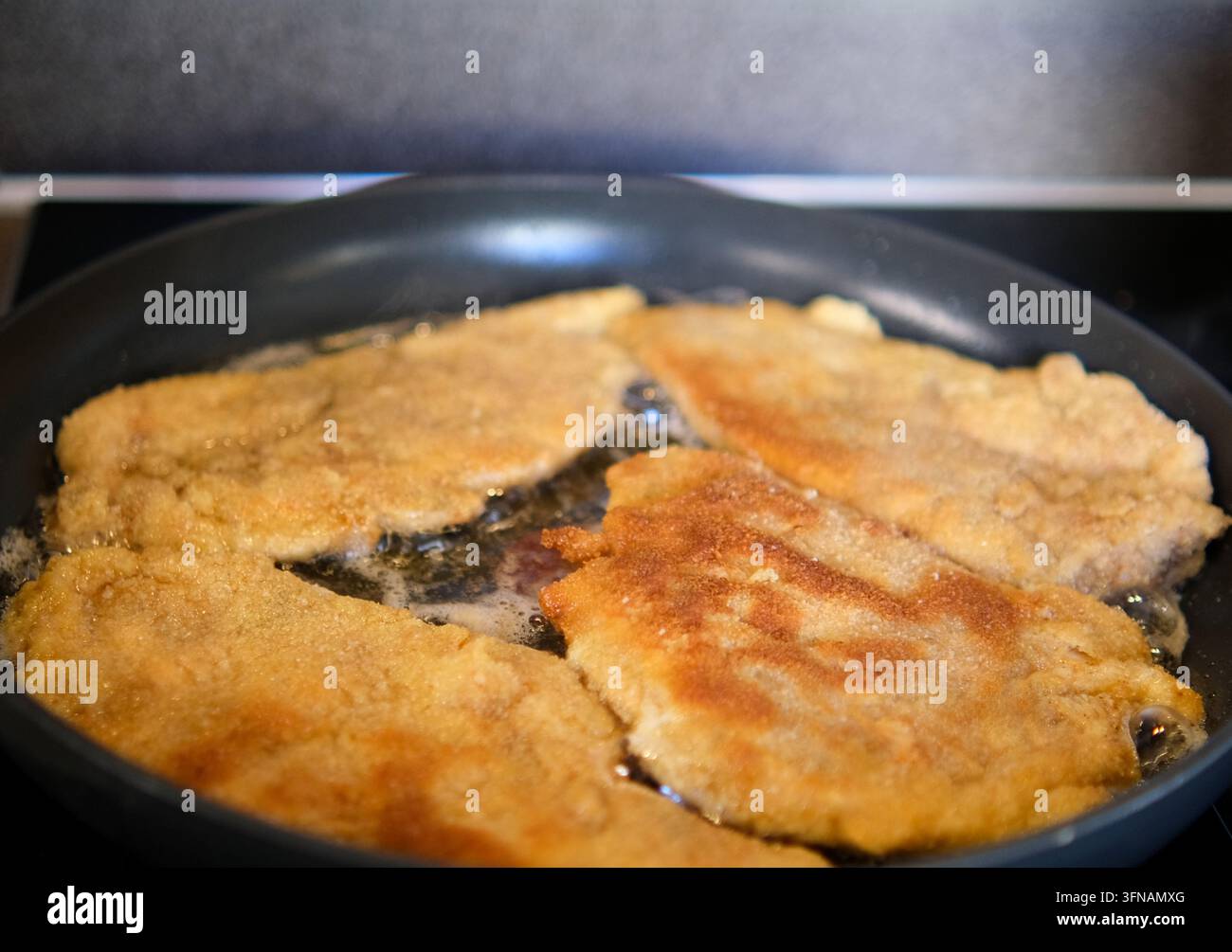 Côtelettes de viande panées croustillantes cuisant et grésillant dans une poêle avec de l'huile Banque D'Images