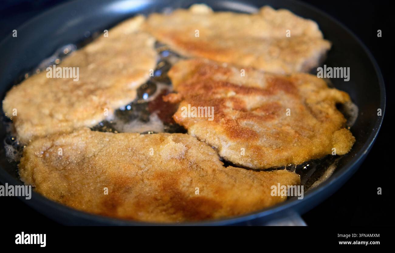Côtelettes de viande panées croustillantes cuisant et grésillant dans une poêle avec de l'huile Banque D'Images