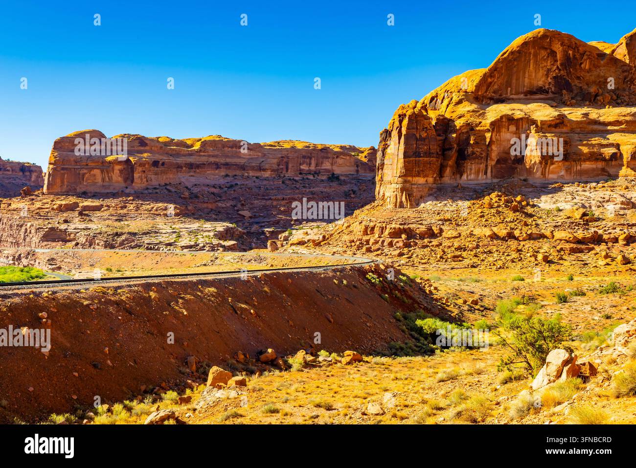 Les voies ferrées longeent des falaises de grès accidentées près du point de départ pittoresque du sentier Corona Arch à l'extérieur de Moab, Utah Banque D'Images