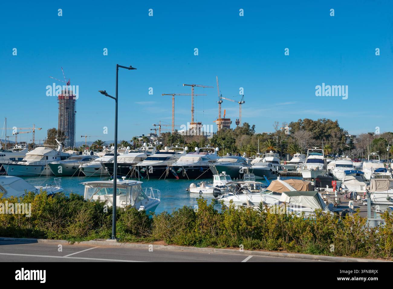ATHÈNES, GRÈCE - 19 FÉVRIER 2026 : Yachts amarrés à la marina de Glyfada avec des grues de construction et la tour Riviera à Ellinikon en arrière-plan à Athènes Banque D'Images