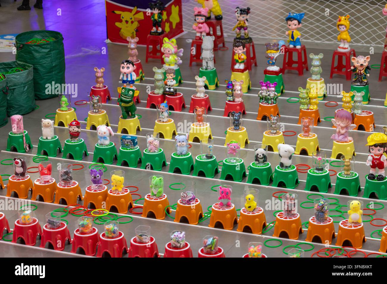 De nombreuses figurines colorées de personnages et petits jouets disposés comme prix pour un jeu de lancer d'anneaux Banque D'Images