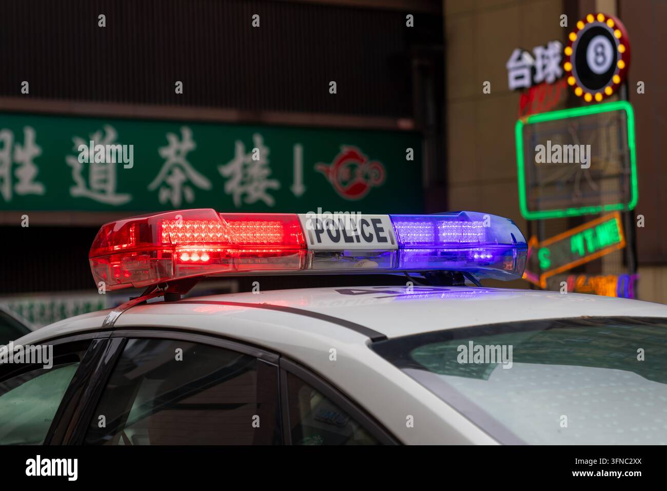 Voiture de police avec des lumières d'urgence rouges et bleues clignotantes sur une rue de ville en Chine Banque D'Images