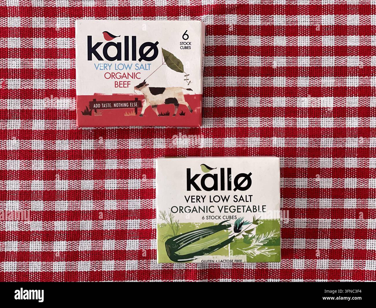 Boîtes de bouillons bio Kallo très faibles en sel, bœuf bio et variété de légumes bio sur une nappe à carreaux rouges - Image de stock capturée avec un smartphone