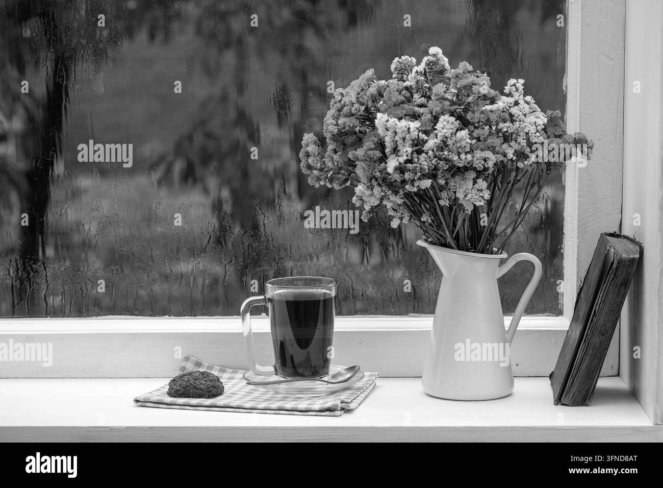 Ancien livre, bouquet de fleurs et tasse de thé sur fond de fenêtre avec gouttes de pluie à la maison par un jour d'été près du jardin, gros plan, espace de copie, noir et Banque D'Images