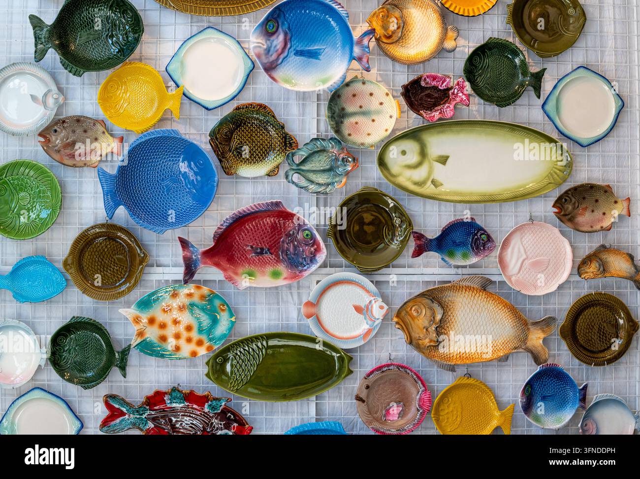 De nombreux assiettes en céramique en forme de poisson disposés ensemble créant un fond coloré Banque D'Images