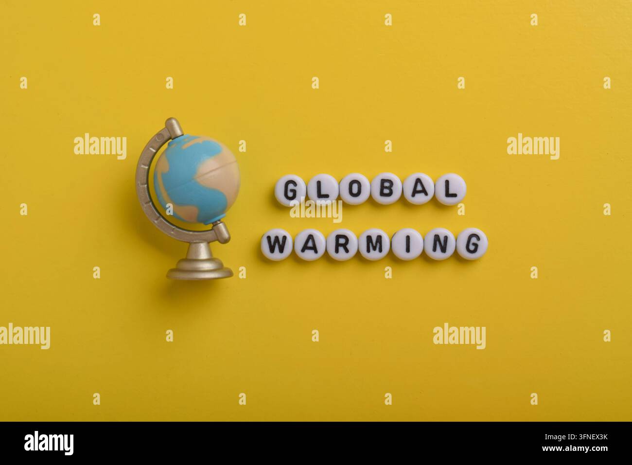 Modèle de globe avec texte sur le réchauffement climatique sur un fond jaune représentant le changement climatique, la hausse des températures, la prise de conscience environnementale, la durabilité Banque D'Images