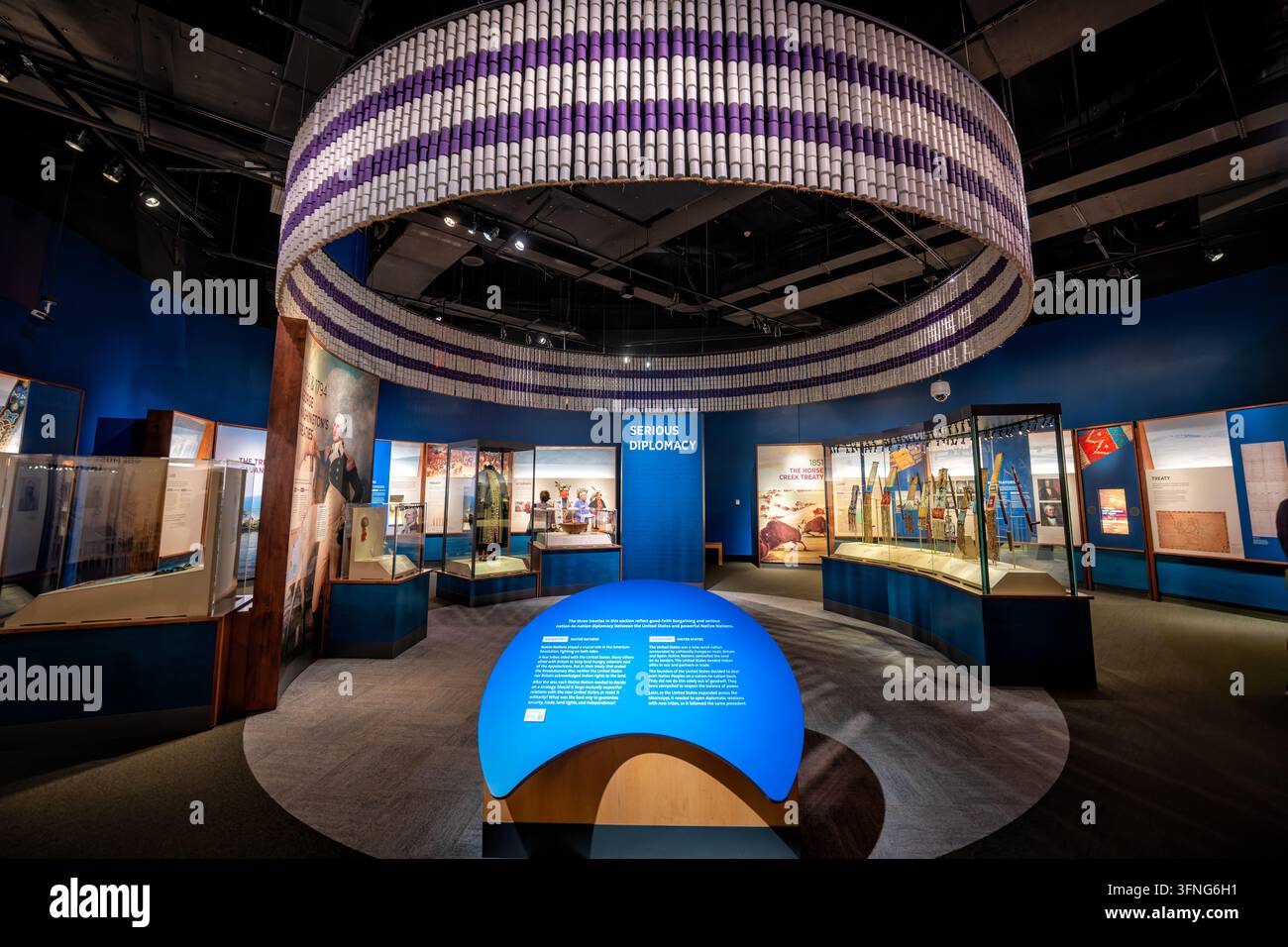 Exposition Nation to Nation Treaty au American Indian Museum | WASHINGTON — Les visiteurs explorent l'exposition "Nation to Nation : Traités entre les États-Unis et les nations amérindiennes" au National Museum of the American Indian sur le National Mall, jeudi 2 octobre 2026. Un anneau tissé inspiré du wampum, suspendu au plafond en bandes violettes et blanches, ancre la galerie circulaire, ouverte en 2014 pour le 10e anniversaire du musée et guest-curratée par Suzan Shown Harjo, une militante Cheyenne et Hodulgee Muscogee. Les vitrines de la section "Serious Diplomacy" examinent les traités Banque D'Images