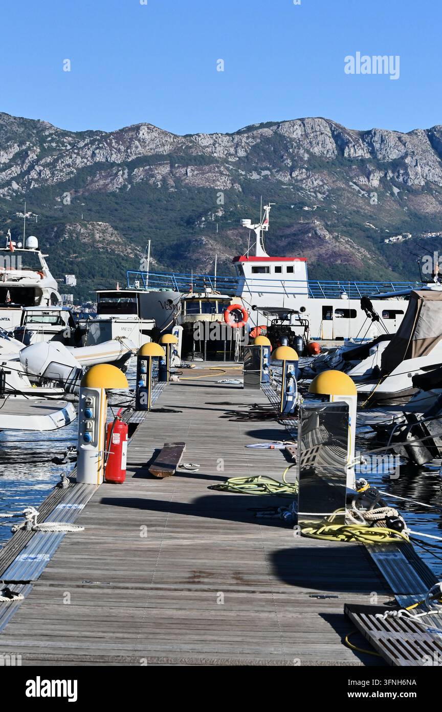 Photographie de stock macro verticale détaillée montrant un ponton de marina en bois avec des yachts, des équipements de sécurité et des cordes à l'extérieur sous la lumière naturelle du jour. Banque D'Images