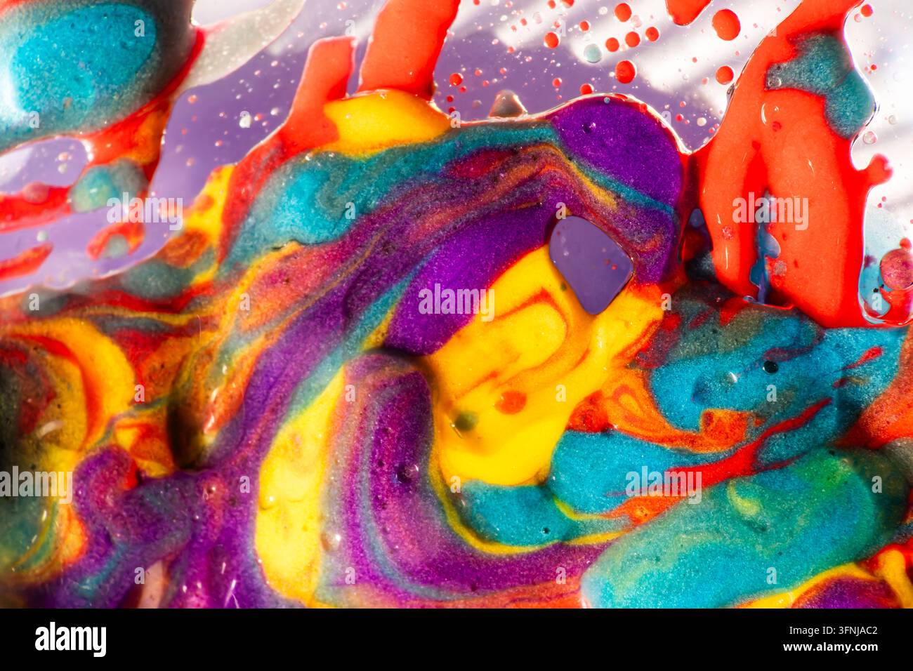 Photographie macro vibrante de peinture jaune, violette, turquoise et rouge tourbillonnante avec des bulles brillantes, créant un fond abstrait énergique avec une richesse Banque D'Images
