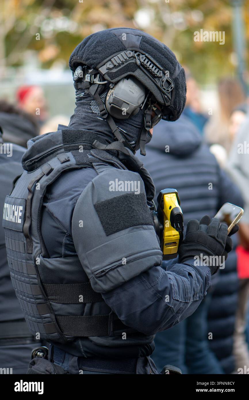 VIENNE, AUTRICHE, 26 octobre 2025 : Un officier de police en équipement tactique est vu de dos tenant un smartphone. Banque D'Images