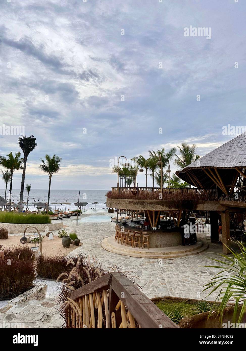 Bar de plage en bambou surplombant l'océan sous les palmiers dans une douce lumière diffuse. - Image de stock capturée avec un smartphone