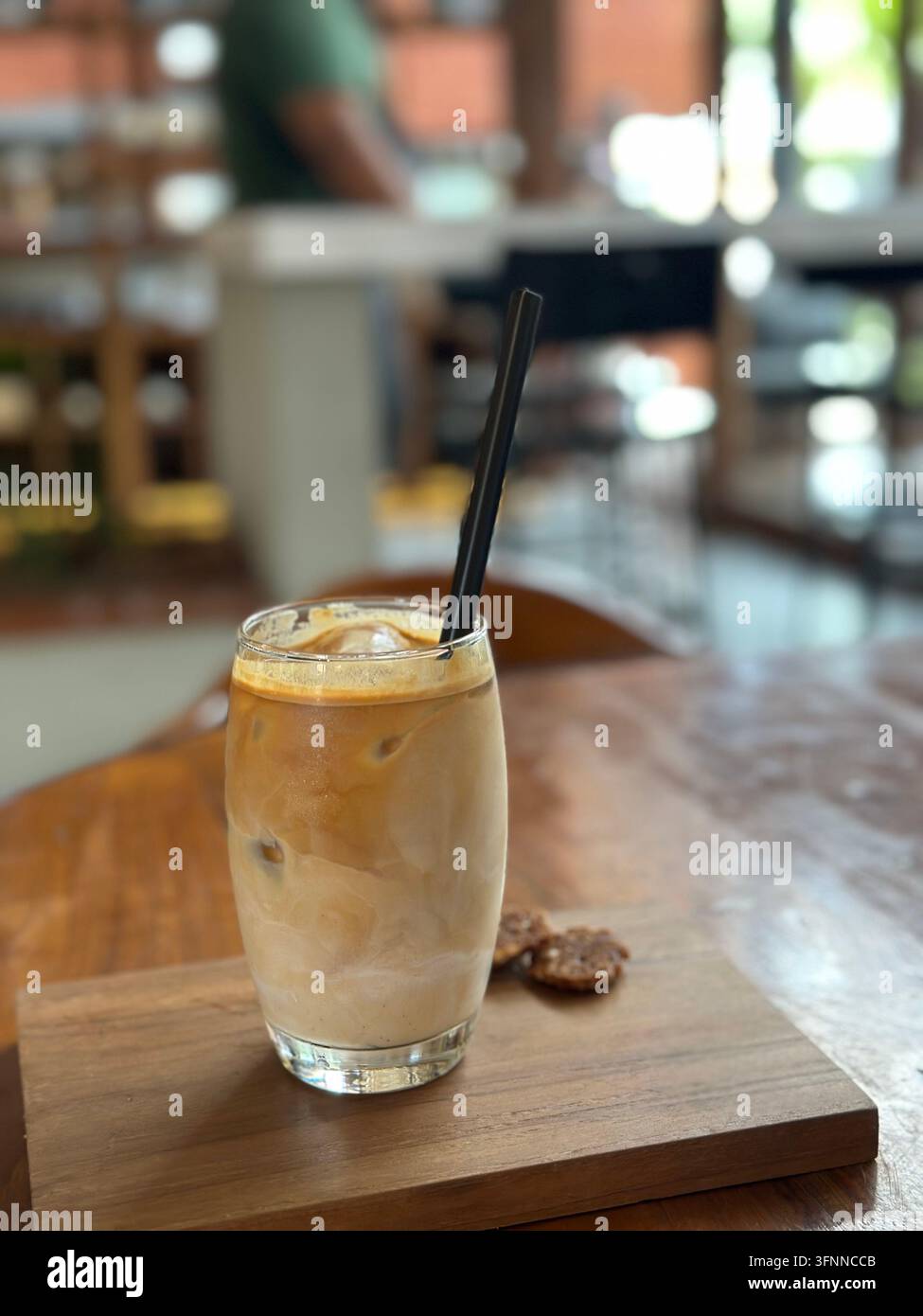 Lait glacé avec des biscuits repose sur une table en bois de café sous une lumière douce du jour. - Image de stock capturée avec un smartphone