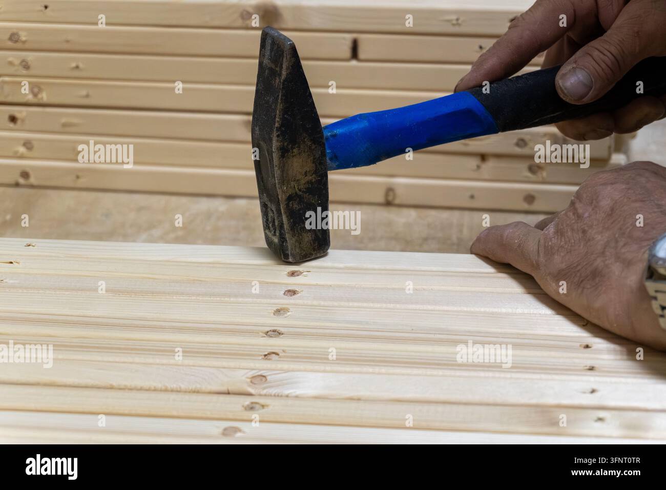 Charpentier enfonçant une cheville en bois dans une planche de bois dans un atelier Banque D'Images