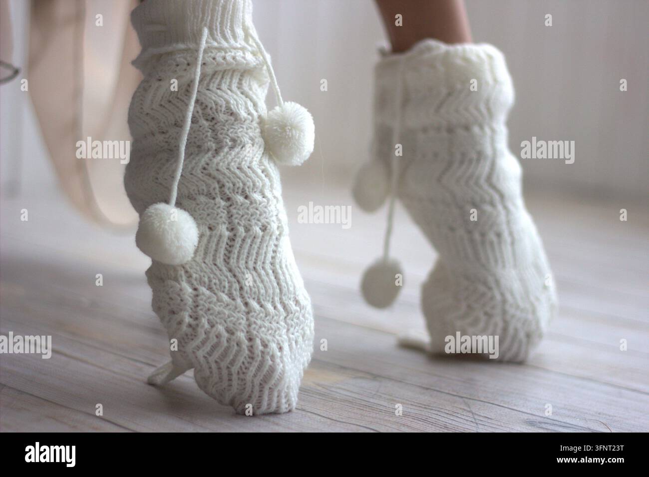 Un plan bas détaillé de pieds féminins en chaussettes de laine chaudes, debout sur la pointe des pieds sur un plancher en bois à l'intérieur, confortable. Banque D'Images