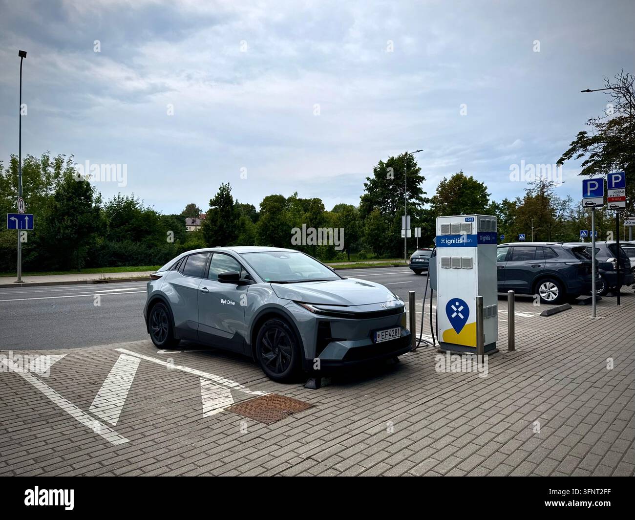Photo verticale d'une voiture électrique grise Toyota bZ4X de Bolt Drive en charge à une station Ignitis ON EV en Lituanie sous une lumière du jour nuageuse. - Image de stock capturée avec un smartphone