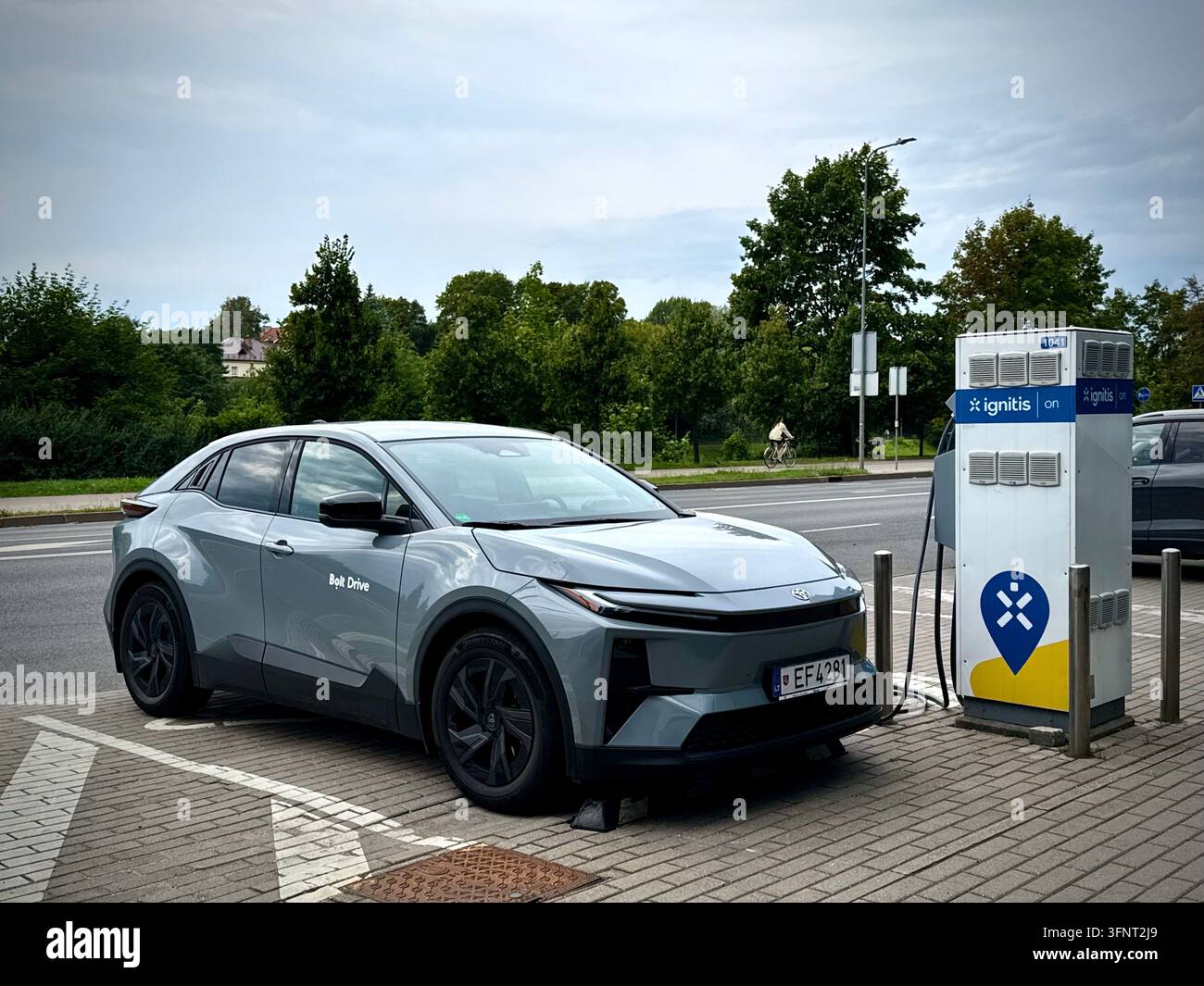 Photo verticale d'une voiture électrique grise Toyota bZ4X de Bolt Drive en charge à une station Ignitis ON EV en Lituanie sous une lumière du jour nuageuse. - Image de stock capturée avec un smartphone