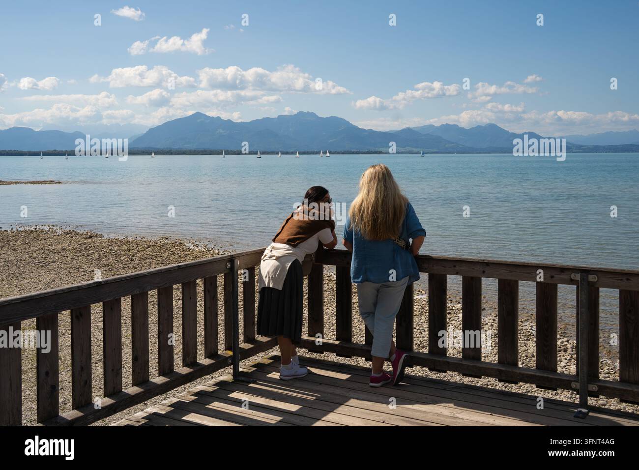 Les visiteurs profitent de la vue panoramique sur le lac Chiemsee depuis la plateforme d'observation de la nature à Chieming, en Haute-Bavière, en Allemagne, avec les Alpes bavarois Banque D'Images
