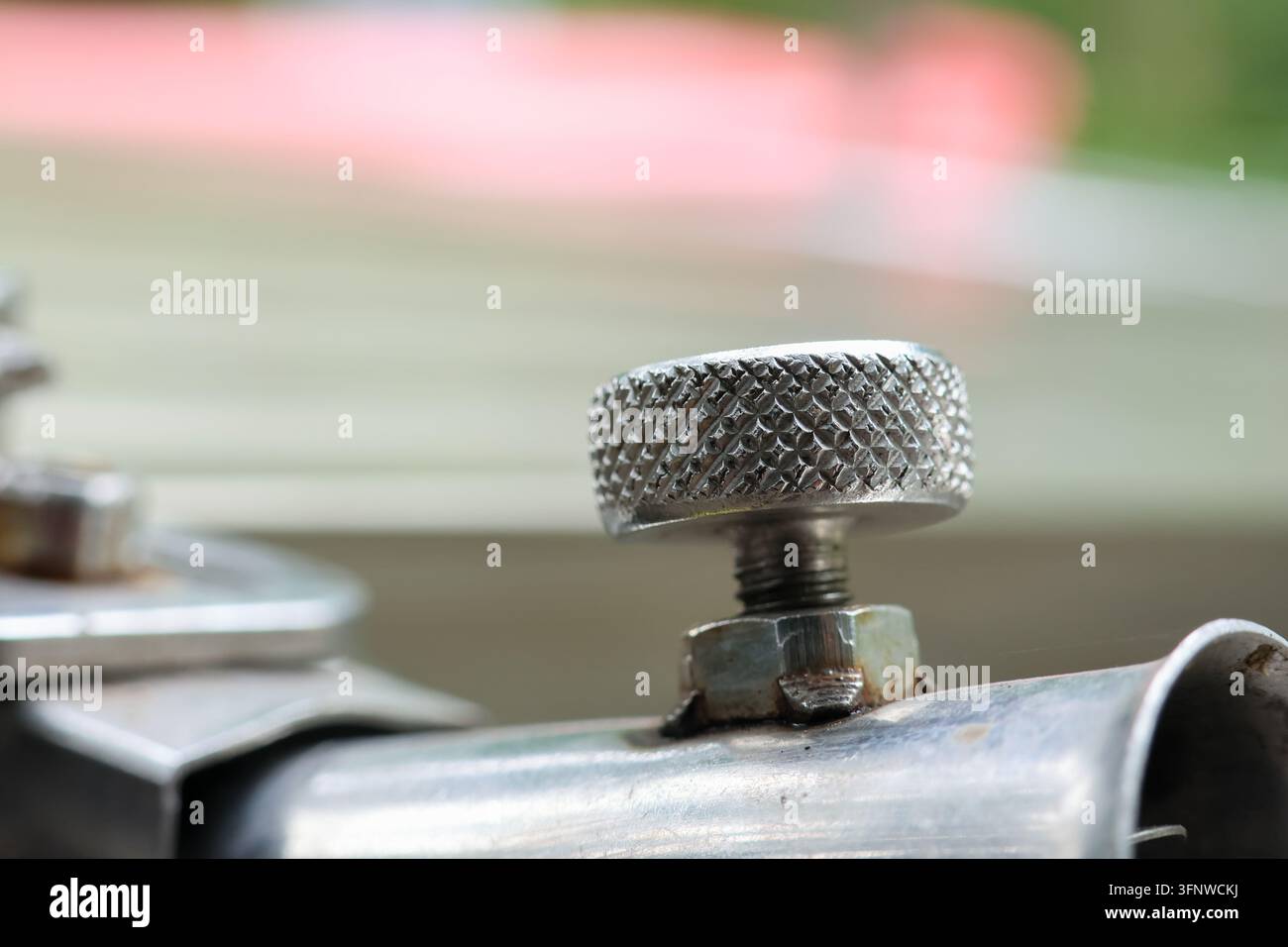 Un bouton de valve en métal sur un tuyau industriel avec une faible profondeur de champ et un arrière-plan doux Banque D'Images