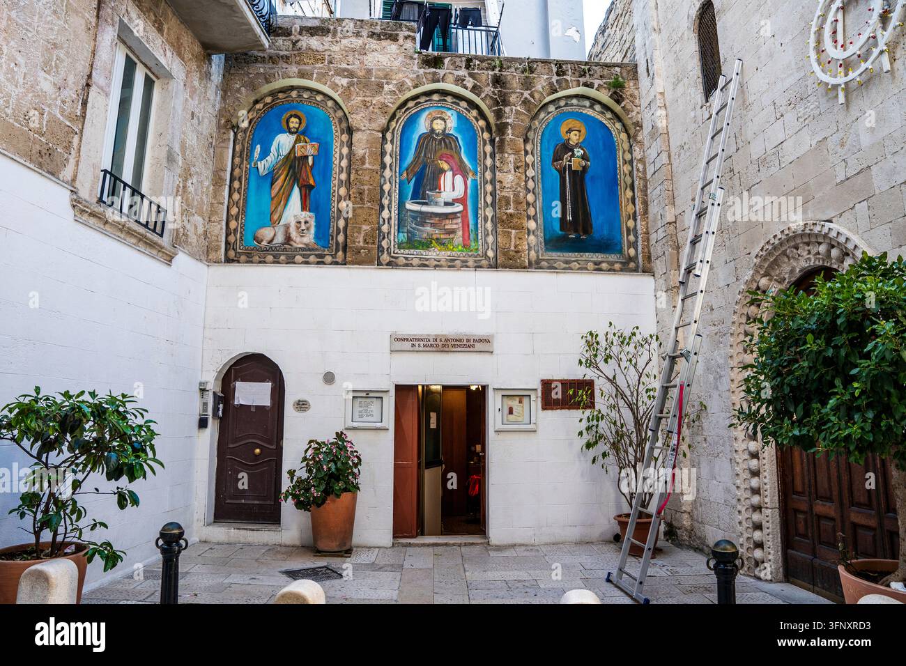 Cour d'église avec des fresques contemporaines colorées de saint Marc, saint François et Jésus à San Marco dei Veneziani, Bari Vecchia, Bari, Pouilles en Italie Banque D'Images