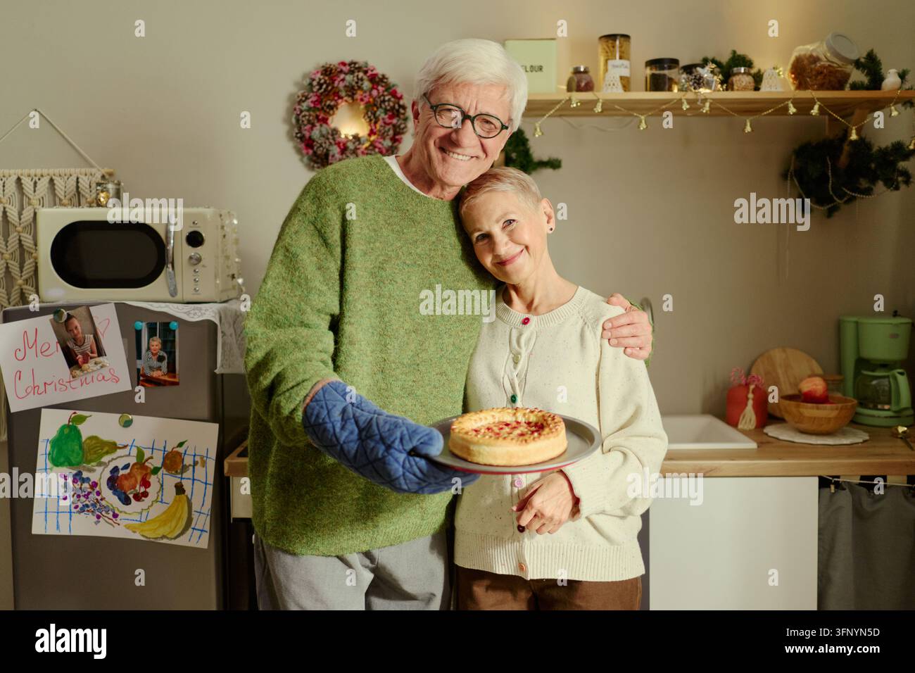 Portrait d'un couple de personnes âgées tenant une tarte fraîchement cuite dans la cuisine Banque D'Images