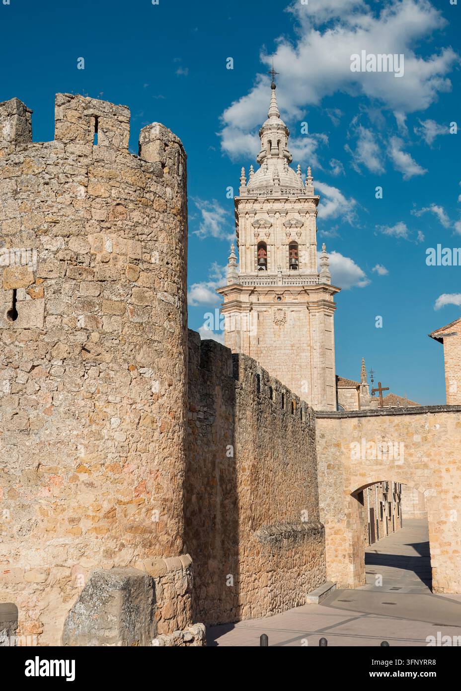 Pierre contre Splendeur : Murs médiévaux encadrant une tour de cathédrale espagnole ornée (El Burgo de Osma, Espagne : 16-jul-2026) Banque D'Images