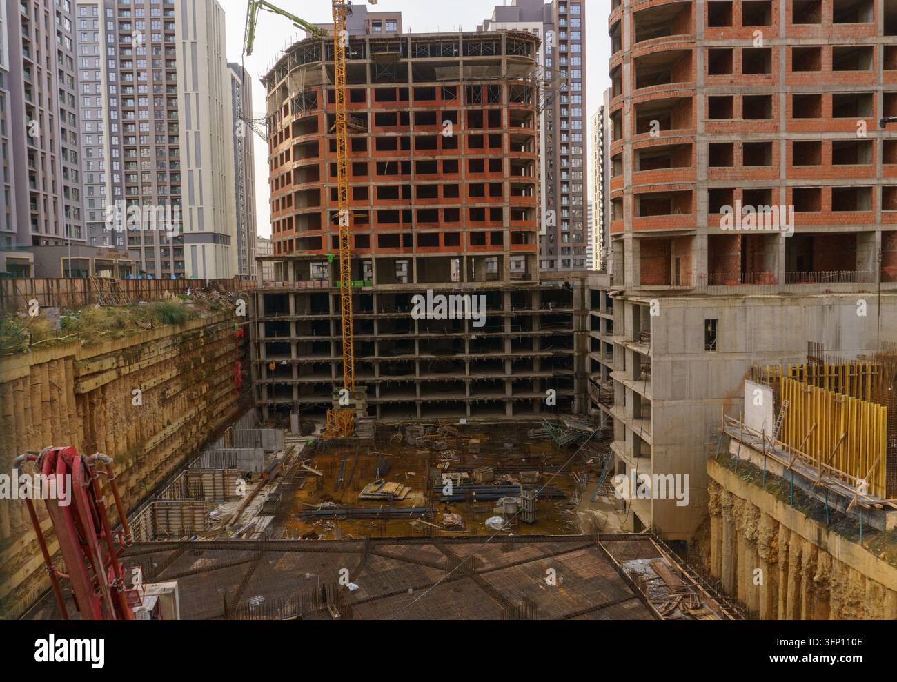 Complexe résidentiel en construction avec une excavation profonde pour un parking souterrain à plusieurs niveaux, des structures en béton armé et une grue tower. Banque D'Images
