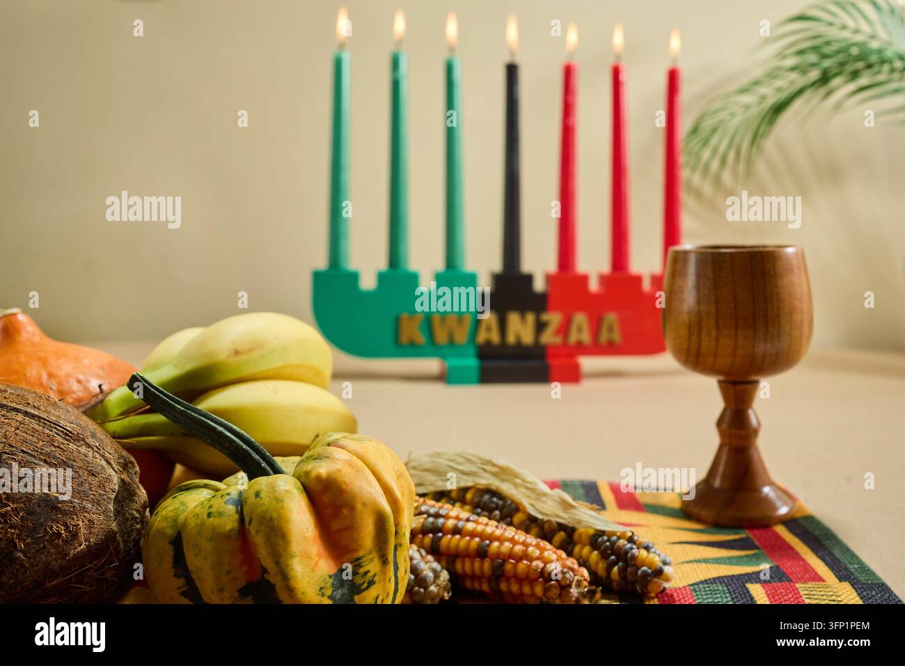 Kinara de Kwanzaa affichant mishumaa saba avec des fruits frais, des légumes et du maïs sur un tapis tissé Banque D'Images