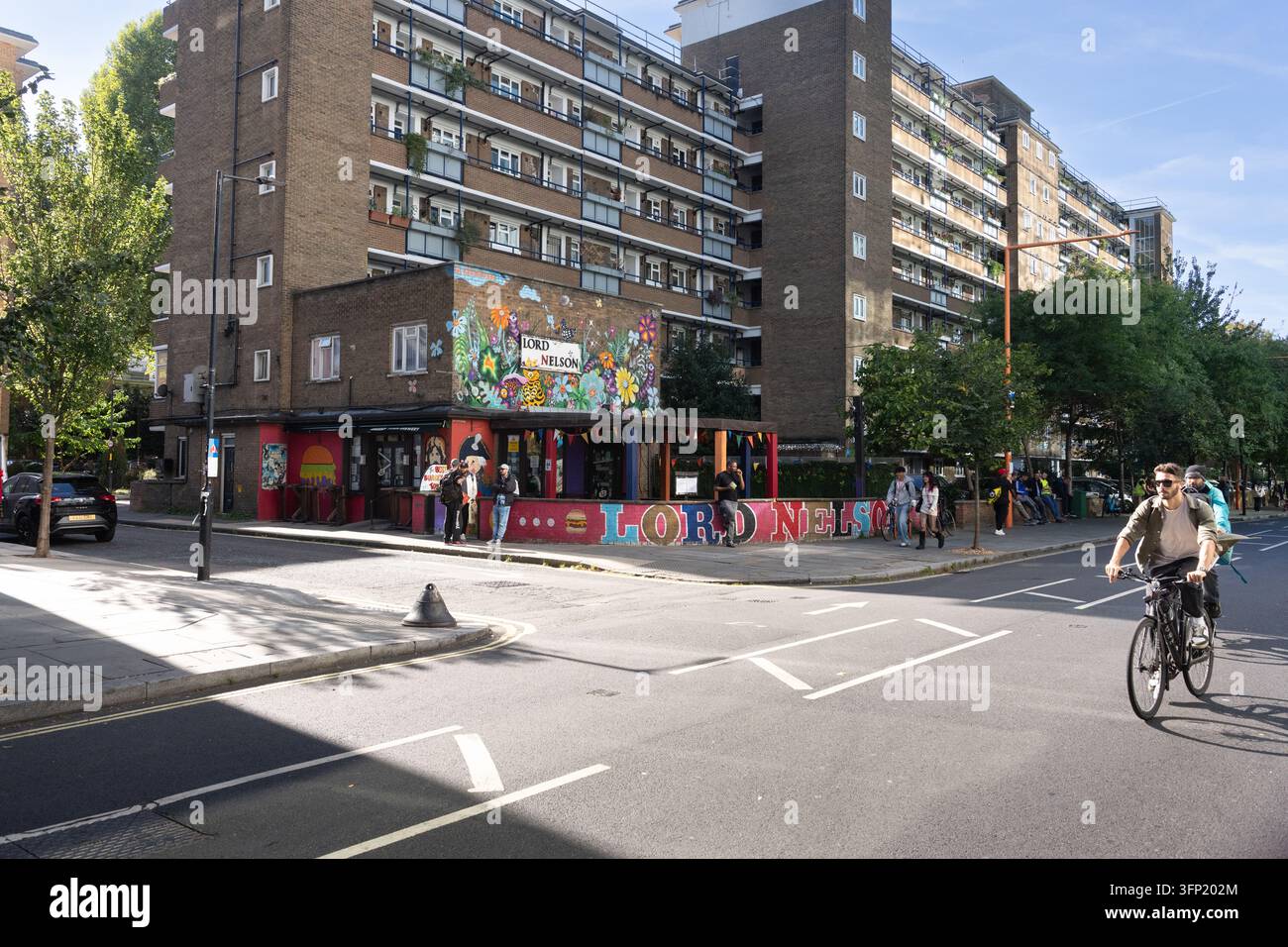 Un cycliste passe devant le pub vibrant Lord Nelson sous un immeuble résidentiel. C'est le Lord Nelson de la Union Street à Londres. Banque D'Images