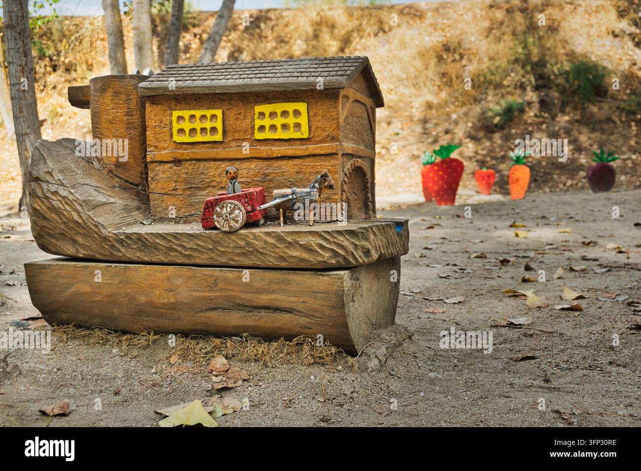 Une ferme en bois sculpté avec un petit cheval et une charrette se trouve près de décorations colorées de fruits et légumes sur le Chemin Magique à Arroyomolinos, en Espagne. Banque D'Images