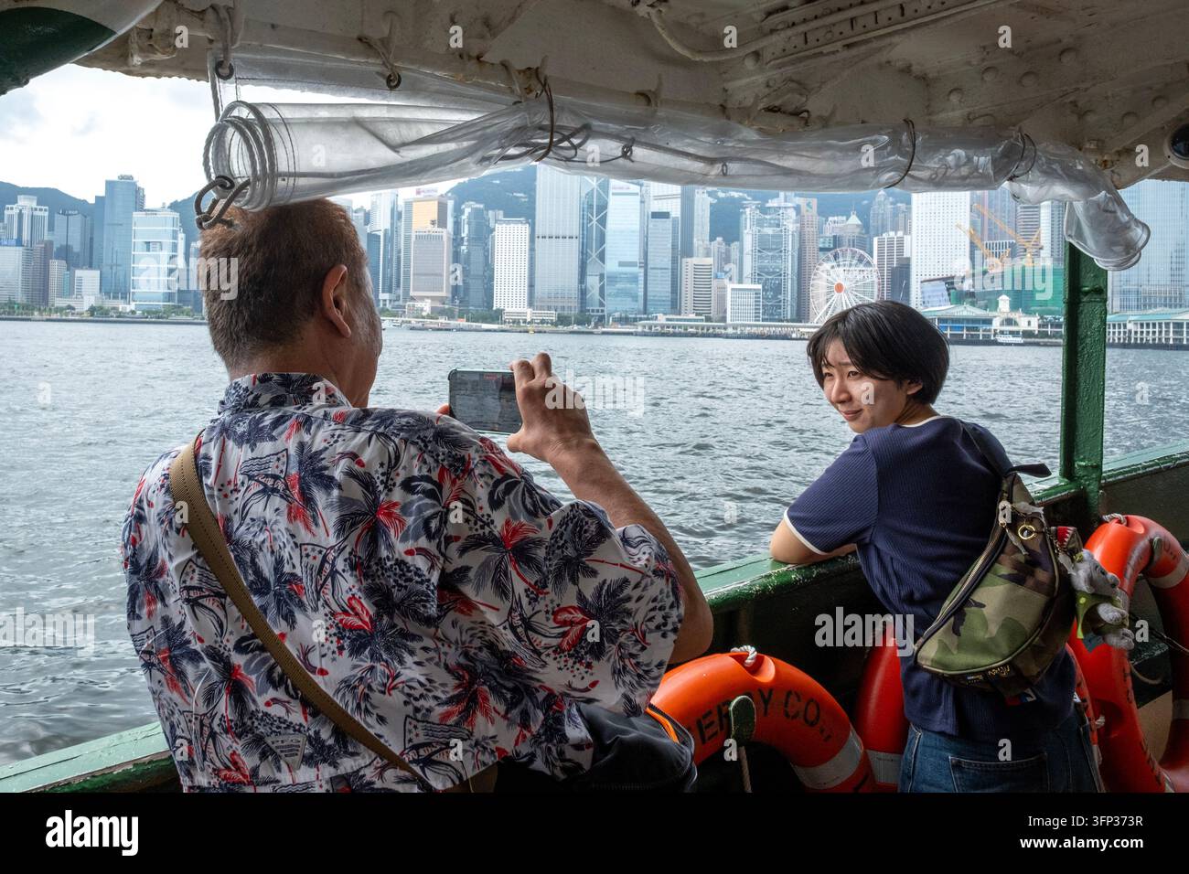 Un touriste prend des photos sur le Star Ferry en traversant le Victoria Harbour à Hong Kong. Banque D'Images