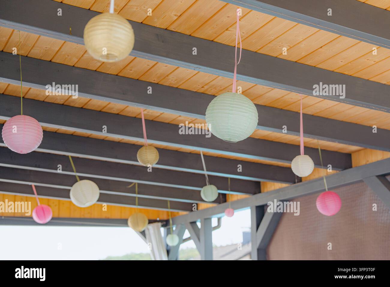 Lanternes en papier suspendues au plafond, avec des lanternes en papier, des poutres en bois, vues de dessus, avec des accents roses et verts et une ambiance festive Banque D'Images
