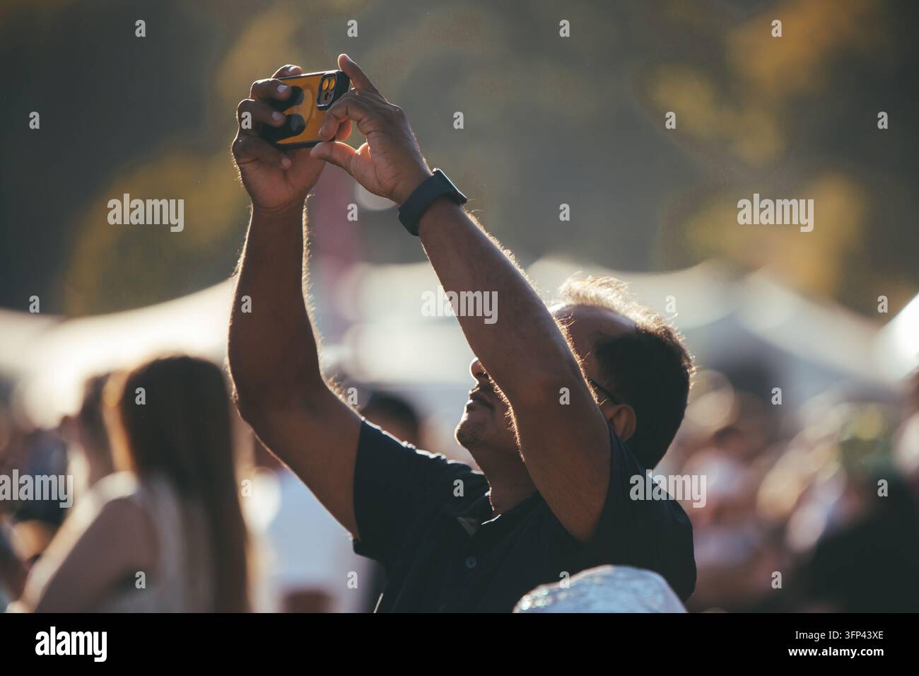 Bristol Balloon Fiesta, 7 août 2026, Royaume-Uni – Homme en silhouette levant son smartphone pour prendre une photo des ballons sous la lumière dorée du crépuscule Banque D'Images