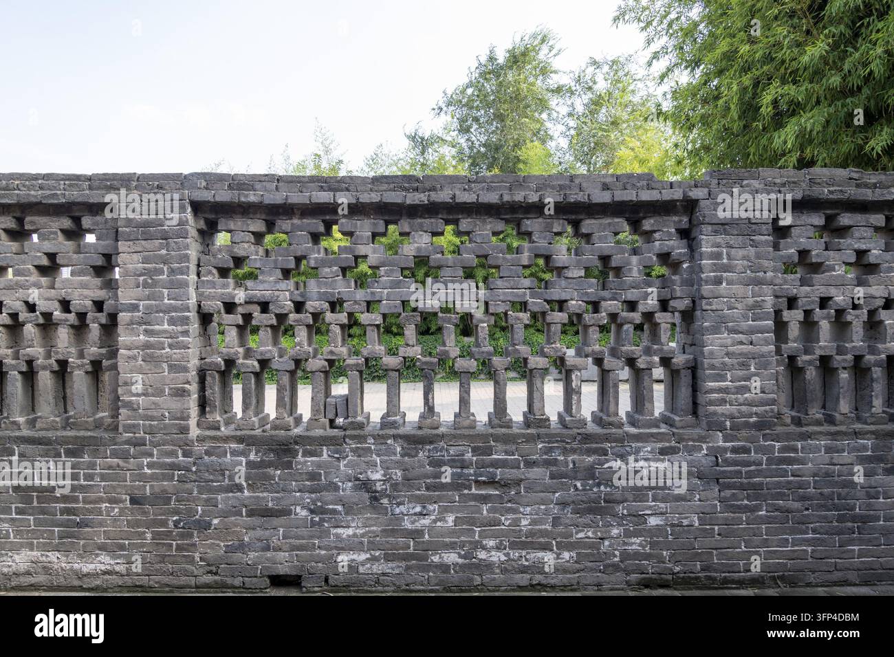 Un mur de briques gris décoratif avec des motifs ajourés et du bambou poussant derrière à Handan, Hebei, Chine. Banque D'Images
