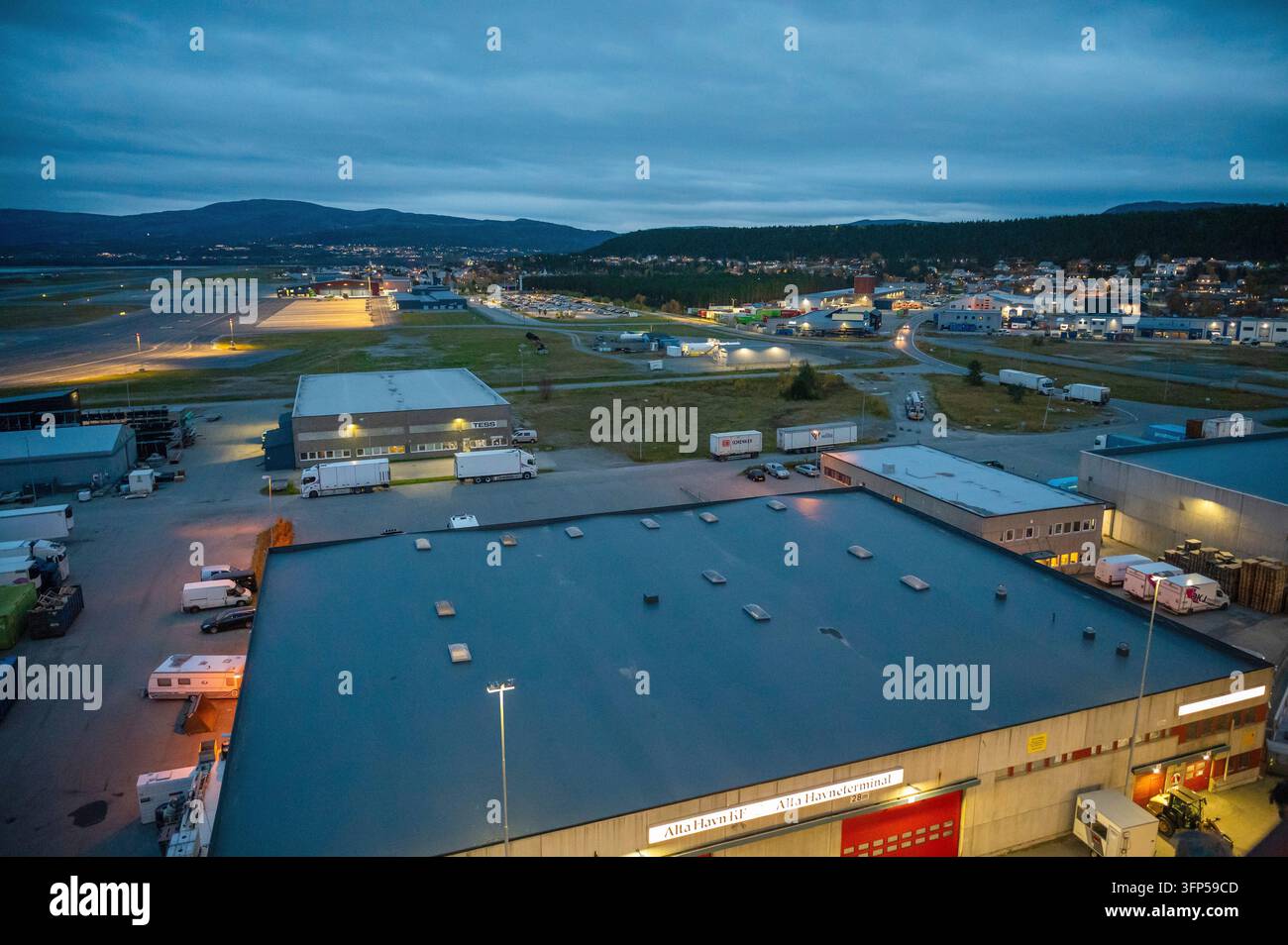 Le bâtiment terminal et la piste de l'aéroport d'Alta illuminés pendant l'heure bleue en Finnmark, dans le nord de la Norvège. Infrastructure aéronautique industrielle en Banque D'Images