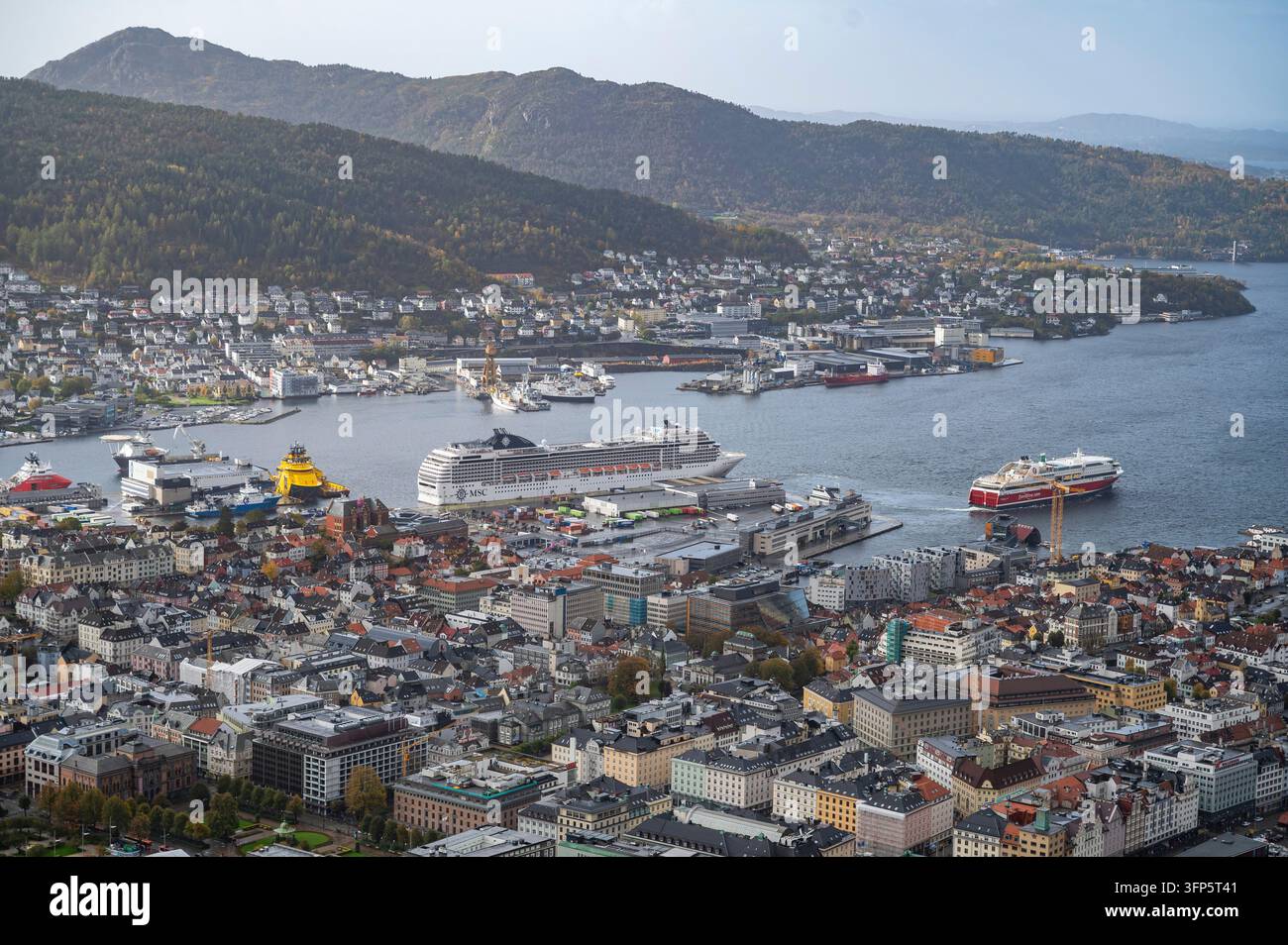 Bergen, Norvège, ville animée par un port rempli de navires de croisière et de ferries, face à des collines ondulantes et un ciel dégagé Banque D'Images