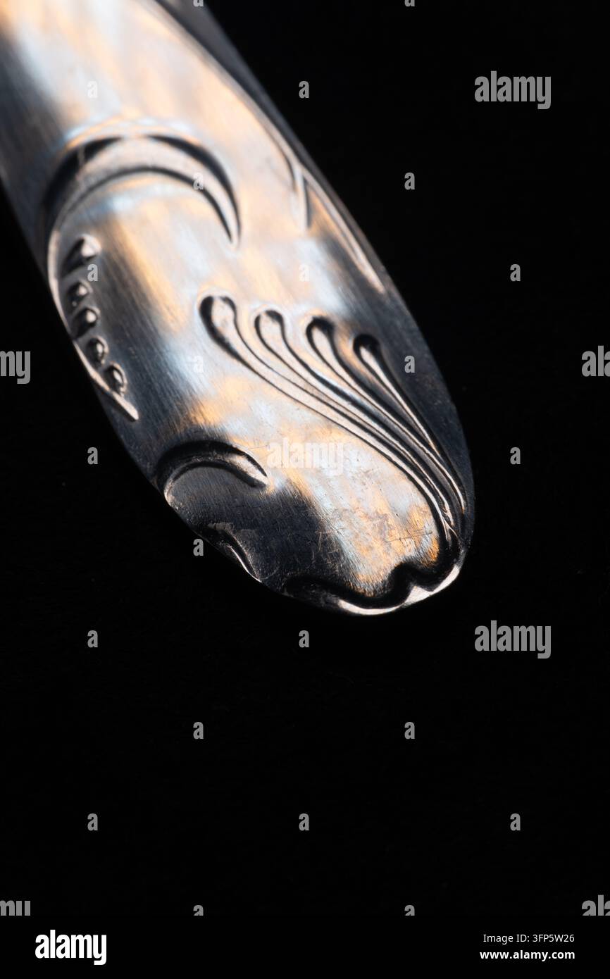Photographie macro mettant l'accent sur la poignée décorée détaillée d'une cuillère ou d'une fourchette en argent vintage avec des gravures élégantes de style art nouveau Banque D'Images