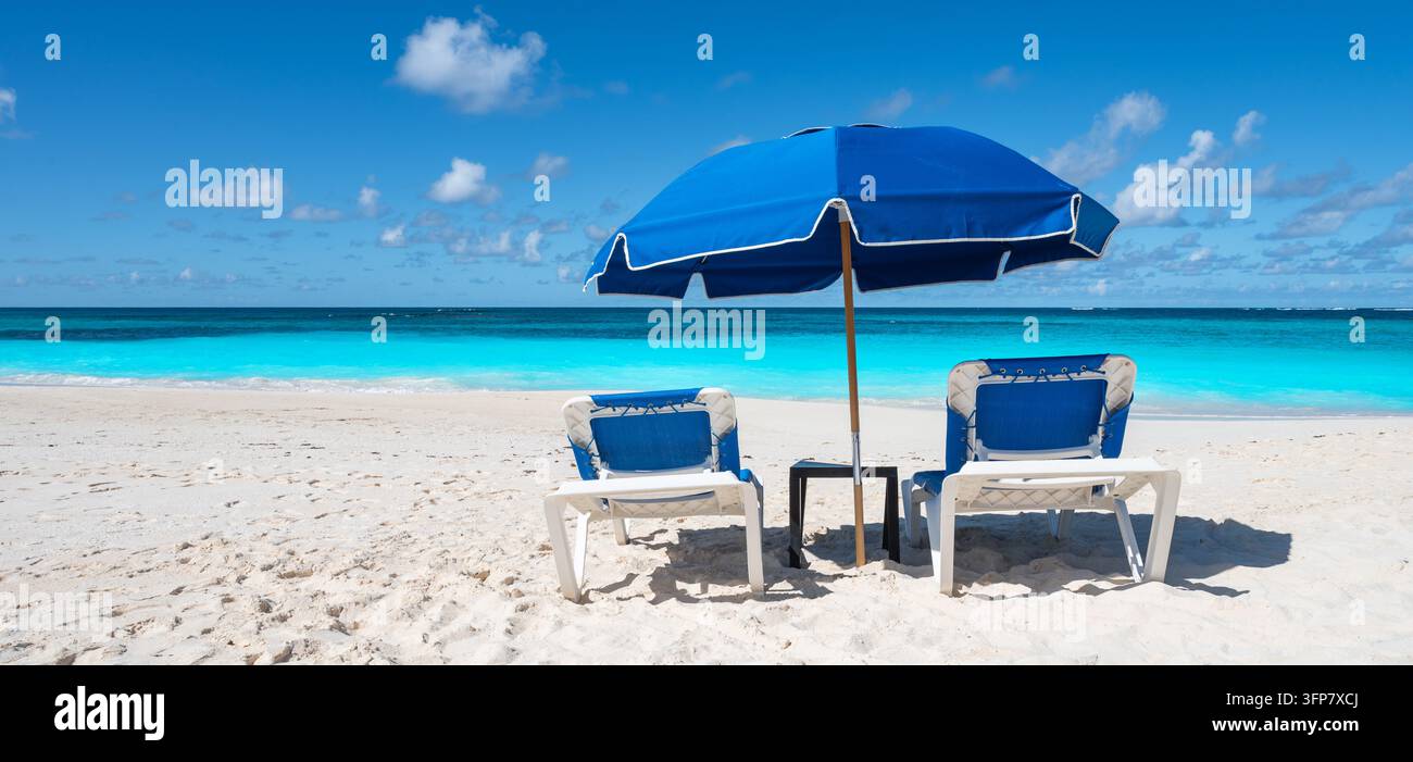 Deux chaises de plage et parasol bleu à Shoal Bay, Anguilla Banque D'Images