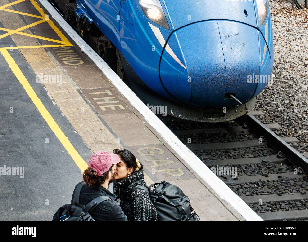 Couple s'embrassant sur le quai de la gare de Newcastle à côté d'un train bleu Southeastern Class 395 Javelin au Royaume-Uni Banque D'Images