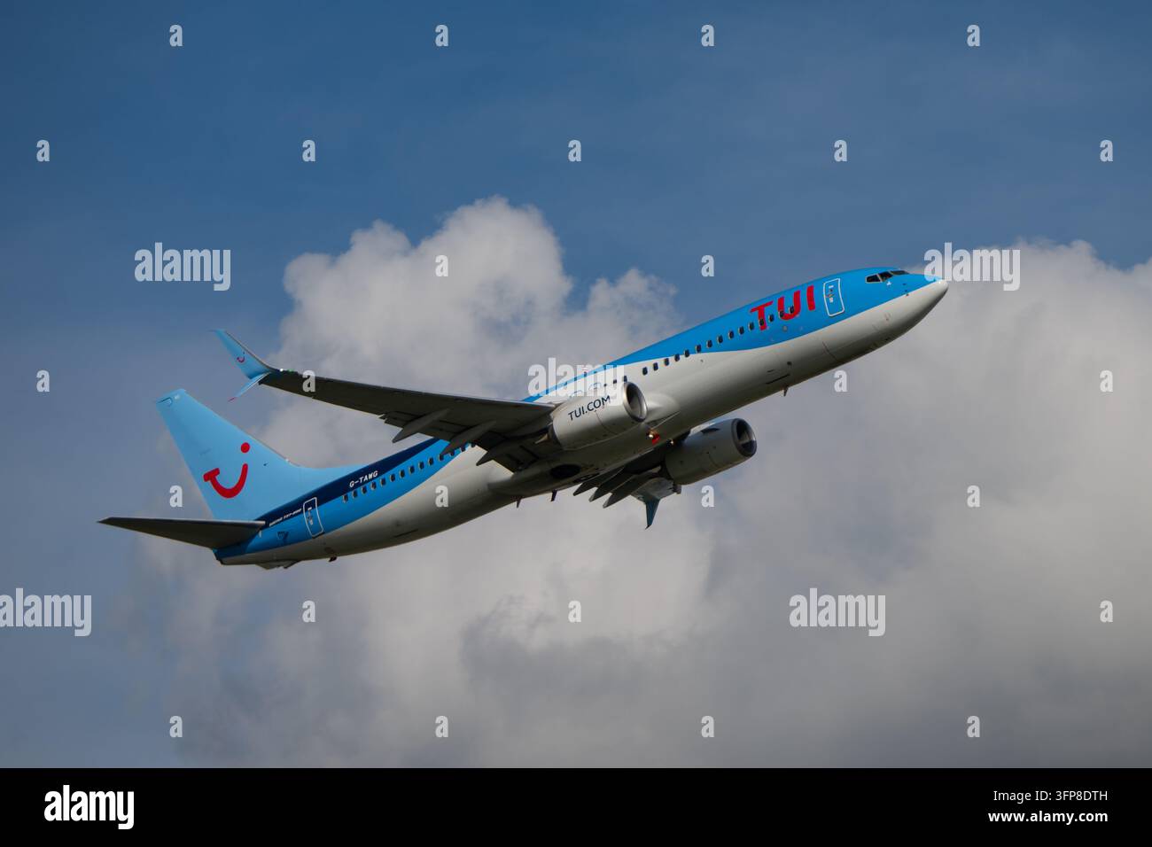 Avion de ligne TUI Airways Boeing 737 MAX 8 s'élevant après le décollage avec le train d'atterrissage en train de se rétracter contre un ciel bleu et des nuages. Banque D'Images