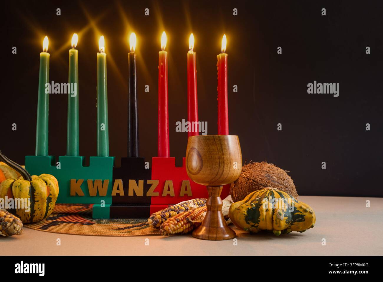 Kinara de Kwanzaa affichant sept bougies mishumaa saba allumées et des symboles de récolte pour la célébration des fêtes Banque D'Images