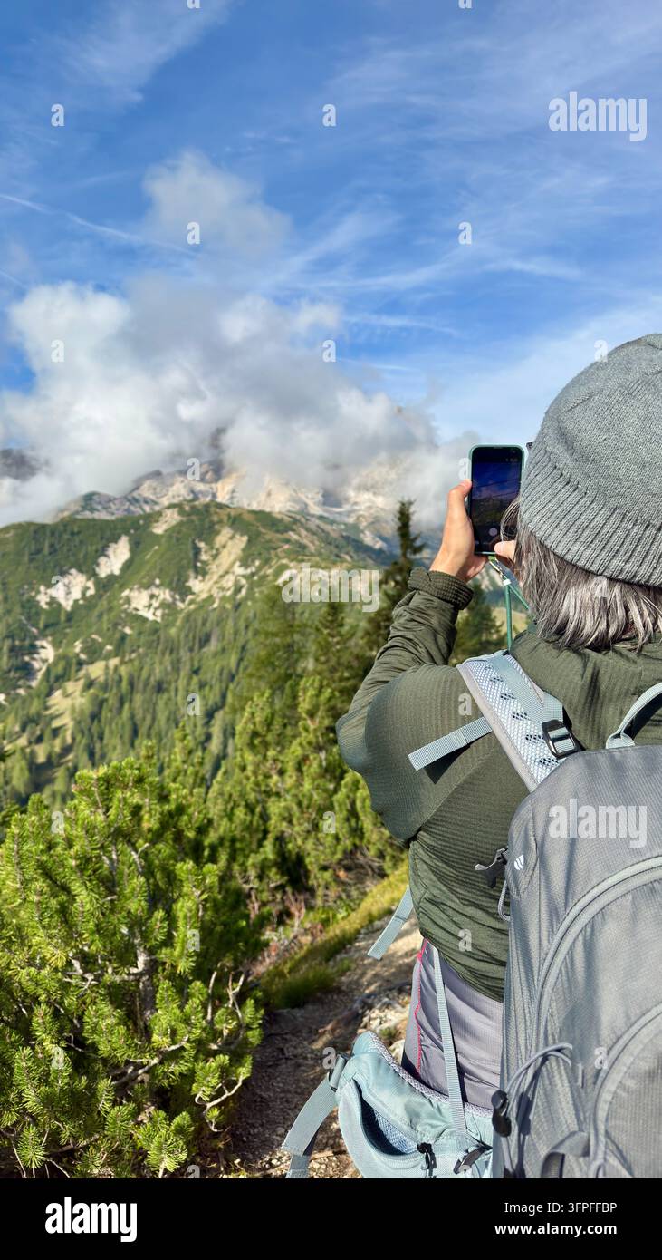 Randonneur utilisant un appareil mobile pour enregistrer la vue panoramique des Dolomites sous un ciel bleu éclatant lors d'un après-midi ensoleillé, Italie Banque D'Images