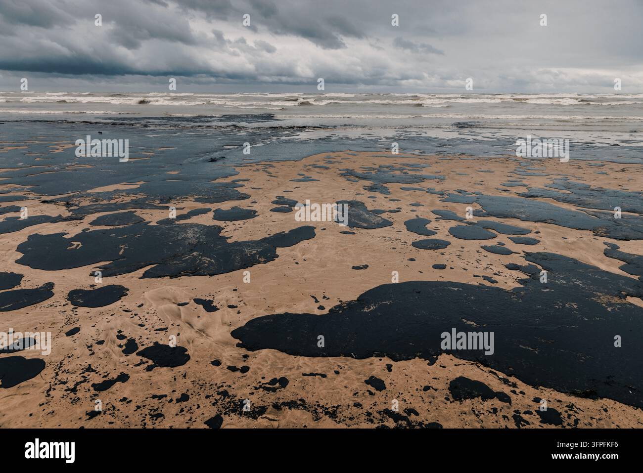 Pollution pétrolière étendue le long d'une côte sablonneuse, illustrant les dommages et les crises de l'environnement marin Banque D'Images