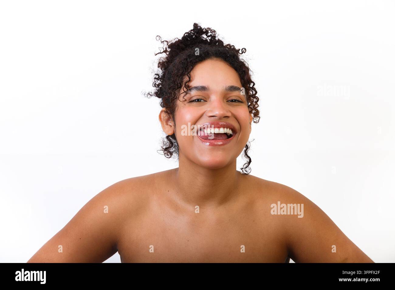 Une femme hispanique montre sa santé cutanée tout en souriant naturellement. Le cadre est simple avec un fond blanc. L'image met l'accent sur l'importance Banque D'Images