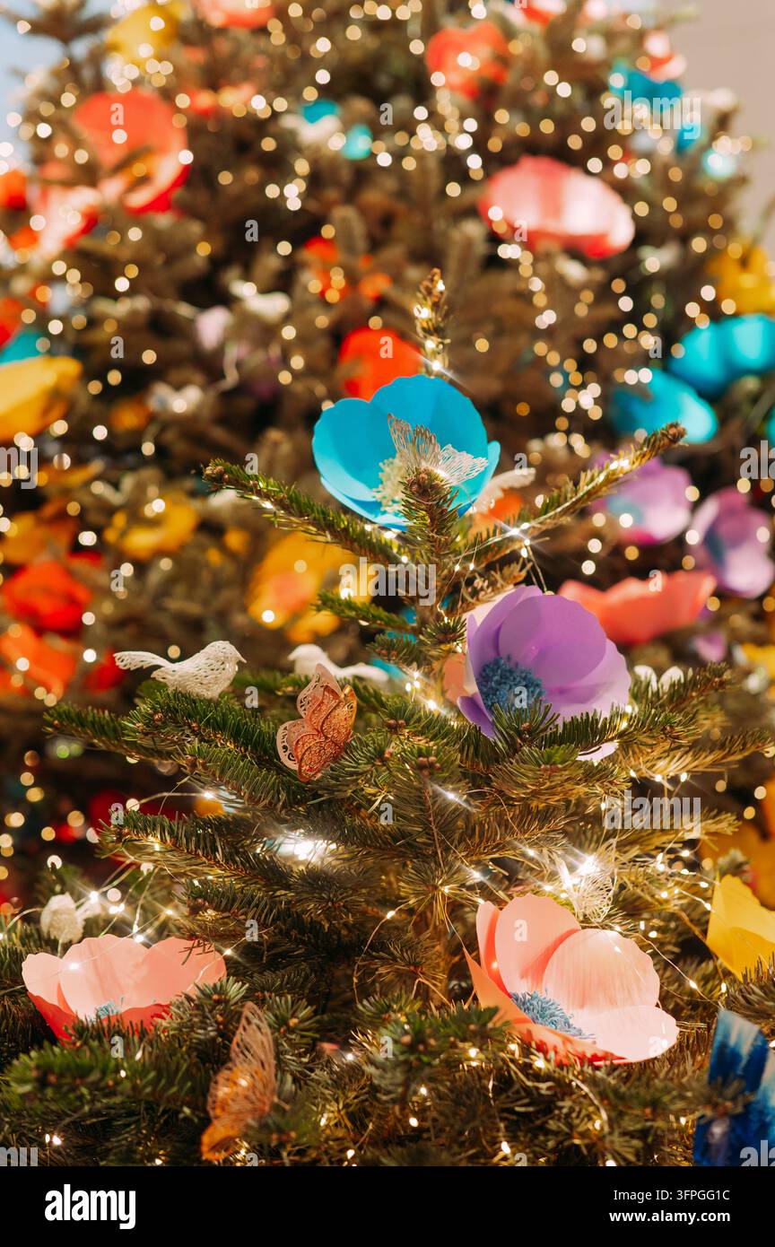 Arbre de Noël coloré avec des fleurs faites à la main et des lumières scintillantes Banque D'Images
