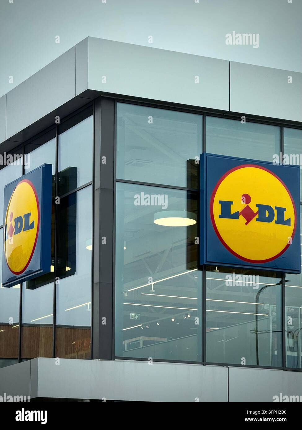 un supermarché Lidl moderne avec des panneaux carrés bleus et jaunes portant le logo, fixés sur un mur-rideau en verre - Image de stock capturée avec un smartphone