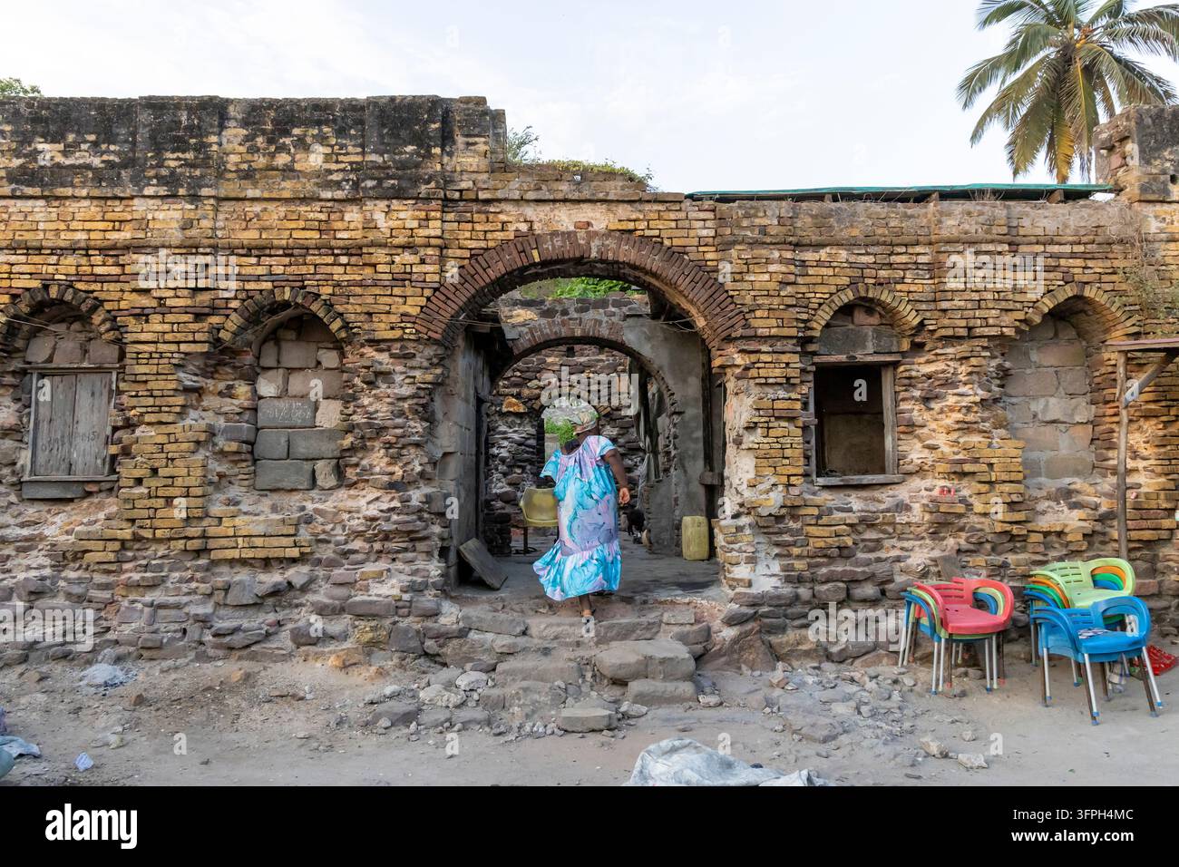 Femme marchant à travers les arches en briques des ruines d'un ancien fort, Région centrale, Elmina, Ghana Banque D'Images