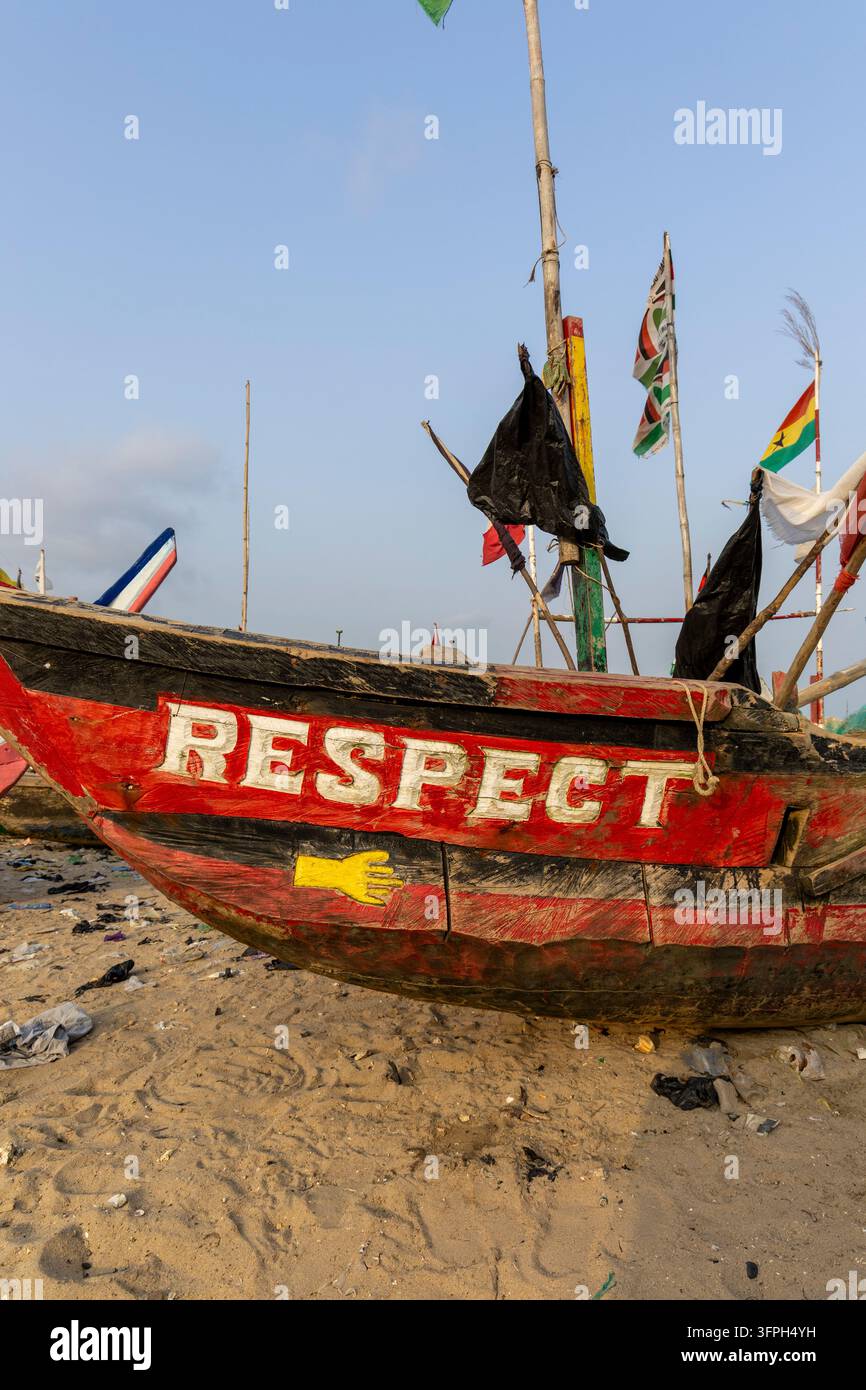 Proue d'un bateau de pêche en bois peint avec le mot Respect et une main jaune sur une plage, Région centrale, Cape Coast, Ghana Banque D'Images