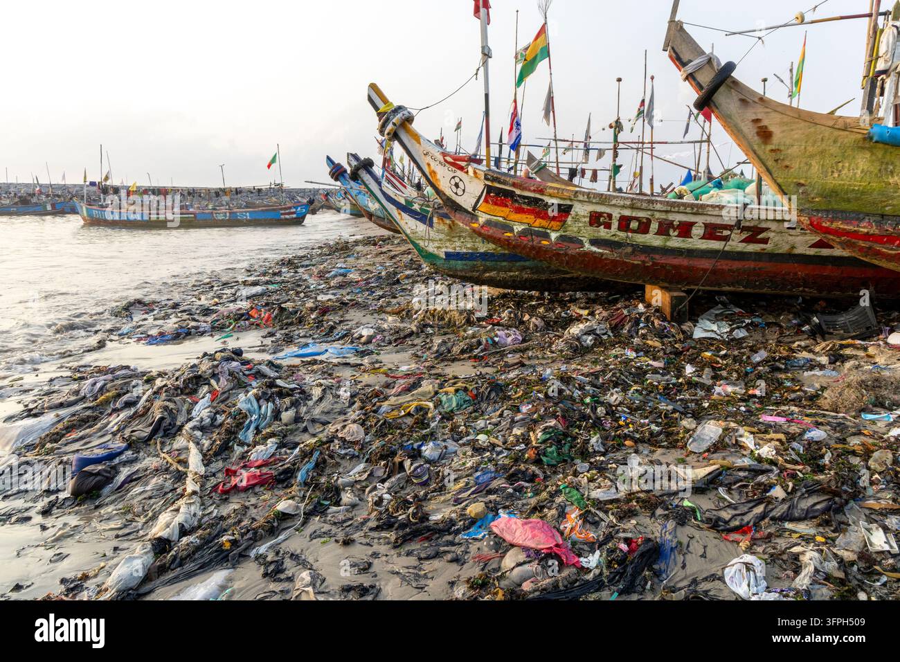 tas de déchets plastiques recouvrant la plage à côté des bateaux de pêche traditionnels, région centrale, Cape Coast, Ghana  Banque D'Images
