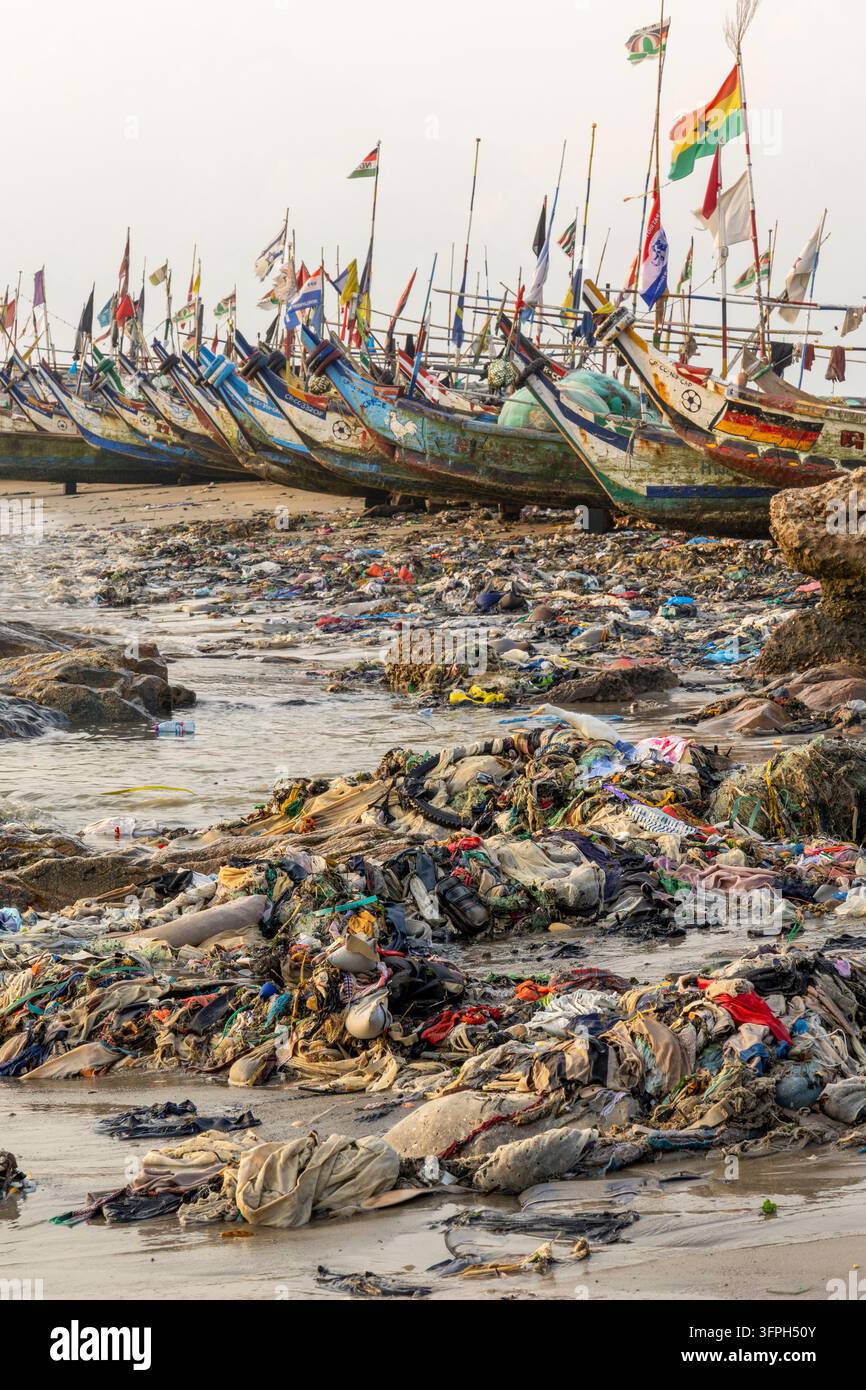 Bateaux de pêche décorés de drapeaux surplombant un énorme tas de déchets plastiques sur la plage, Région centrale, Cape Coast, Ghana Banque D'Images